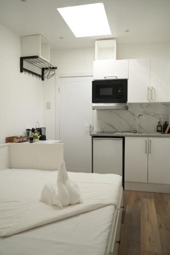 a white kitchen with a bed and a microwave at Concept Rooms in Enfield