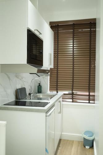 a white kitchen with a sink and a window at Concept Rooms in Enfield