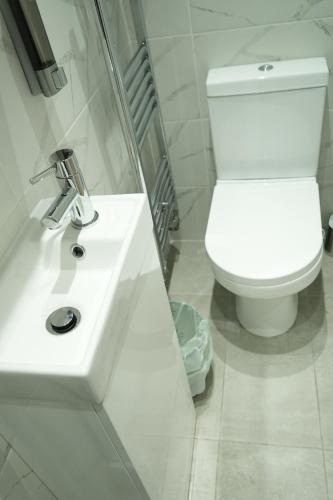 a white bathroom with a toilet and a sink at Concept Rooms in Enfield