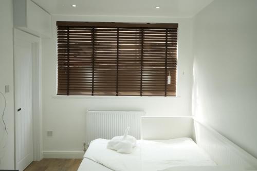 a white bedroom with a bed and a window at Concept Rooms in Enfield