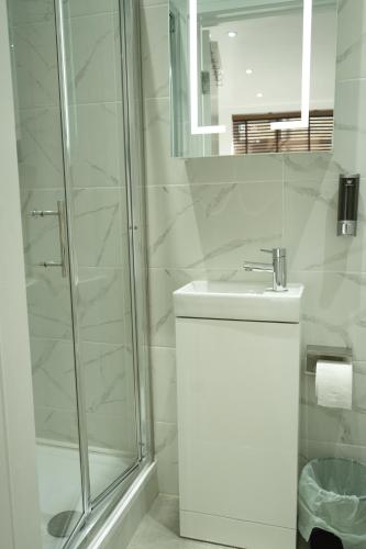 a white bathroom with a shower and a sink at Concept Rooms in Enfield