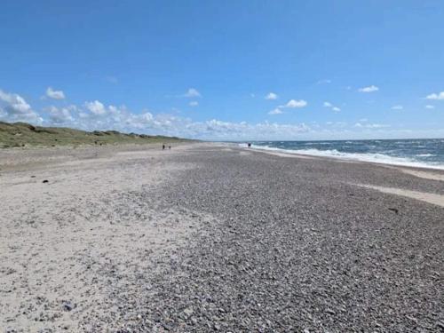a beach with a rocky shoreline and the ocean at 4 star holiday home in Nørre Nebel in Nørre Nebel
