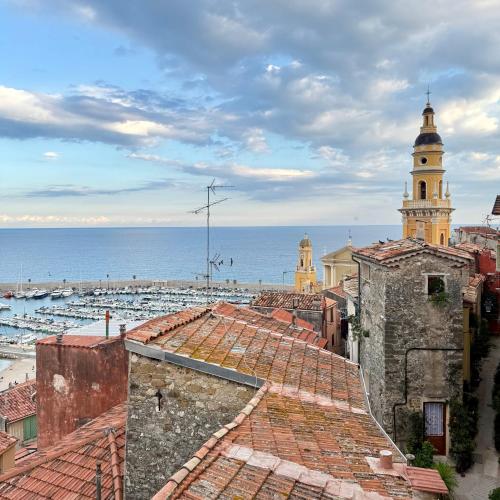 a view of the roofs of a city with the ocean at La Résidence du Vieux Château - Splendide Vue Mer in Menton