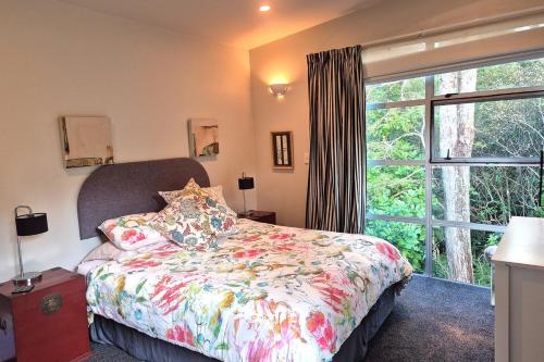 a bedroom with a bed and a large window at beach bush retreat at Leigh in Leigh