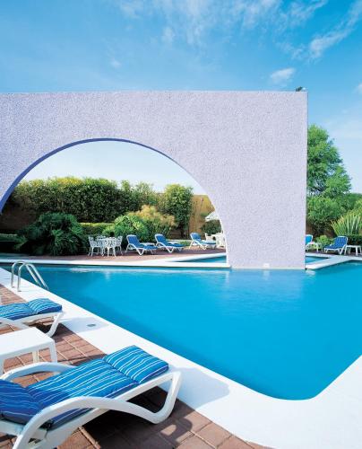 a swimming pool with lounge chairs next to a swimming pool at Fiesta Inn Aguascalientes in Aguascalientes