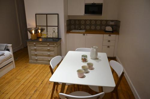 eine Küche mit einem Tisch und Stühlen mit Tassen drauf in der Unterkunft Appartements de Jules & Victoire in Pornic