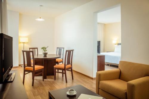 a living room with a table and chairs and a bed at Fiesta Inn Aguascalientes in Aguascalientes