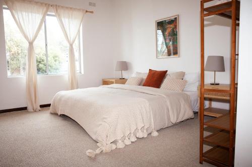 a bedroom with a large white bed with a ladder at Nest at Maggies in Melbourne