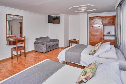 a hotel room with two beds and a chair at Hotel Virrey Central in Bogotá