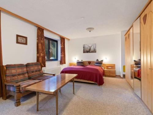 a bedroom with a bed and a couch and a table at Landhaus Herz der Tauern in Mallnitz