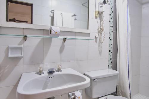 a white bathroom with a sink and a toilet at Hotel Virrey Central in Bogotá