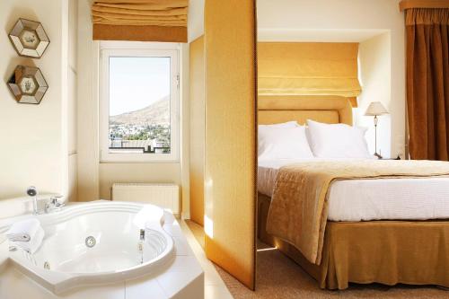 Ayía ParaskevíにあるCasa Taylor 4BR with private pool and sea viewのベッドとバスタブ付きのホテルルームです。