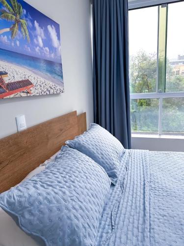 a bedroom with a bed with a blue blanket and a window at Residencial Spader - Bombinhas in Bombinhas