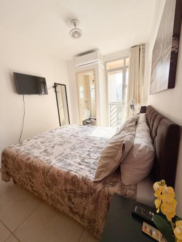 a bedroom with a bed and a couch and a television at Apto Centro cambui em Campinas in Campinas