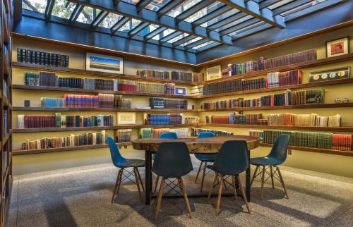 a room filled with tables and chairs with bookshelves at Hotel Criol in Querétaro