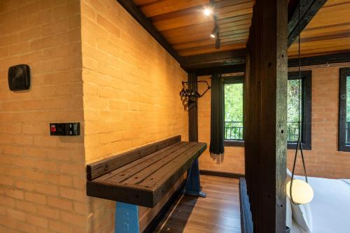 a wooden bench in a room with a brick wall at Casa Container 80 in Campos do Jordão