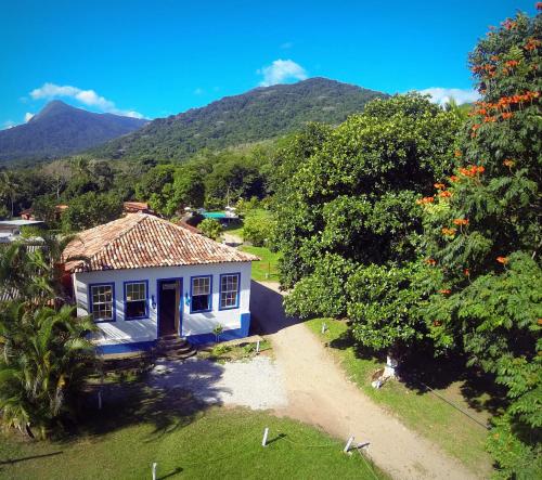 a small white house with mountains in the background at VELINN Pousada Bromelias in Ilhabela