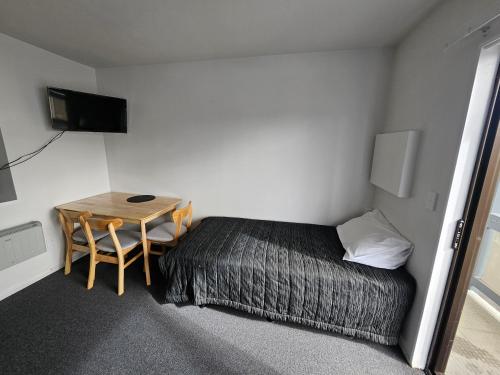 a small room with a bed and a table at 88 Wallace Court Motel - Free Parking in Wellington