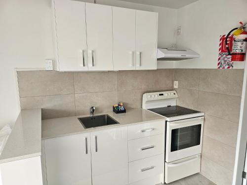 a kitchen with white cabinets and a sink at 88 Wallace Court Motel - Free Parking in Wellington