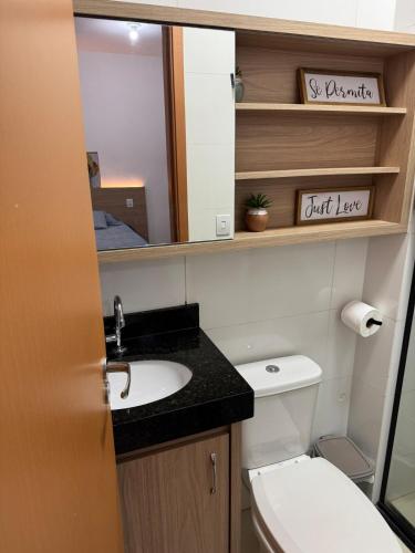 a bathroom with a toilet and a sink and a mirror at Blue Life Torre 1 in Anápolis