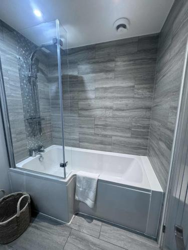 a bathroom with a bath tub with a shower at ROSE-WOOD Gatwick in Horley