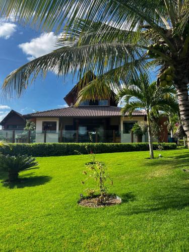 a house with a palm tree in a yard at Bangalô aconchegante e luxuoso Winterville Resort Gravatá PE in Gravatá