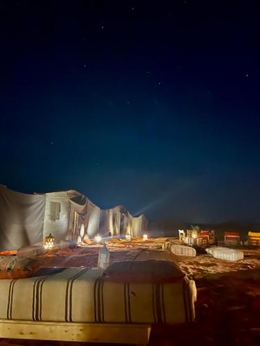 a bed in the middle of a field at night at Mhamid Sahara Luxury Camp - Chez Naji in Mhamid