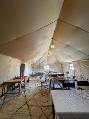 a large tent with tables and chairs in it at Mhamid Sahara Luxury Camp - Chez Naji in Mhamid