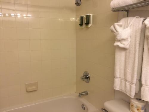 a bathroom with a tub and a toilet and towels at Super 8 by Wyndham Drayton Valley in Drayton Valley