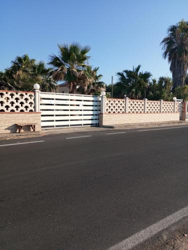 a white fence with a bench next to a street at Oasi Relax in Rodi Garganico