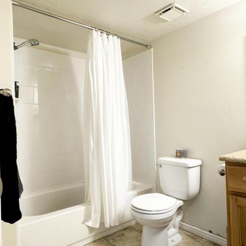 a white bathroom with a toilet and a shower at Focus & Chill Orem Fast WiFi and Home Theatre in Orem