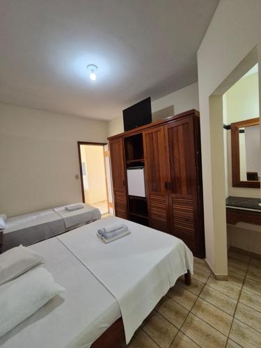 a hotel room with two beds and a television at Pousada Enseada do Corsário in Guarapari