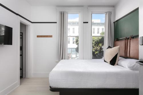 a white bedroom with a large bed and windows at La Ventana in San Diego