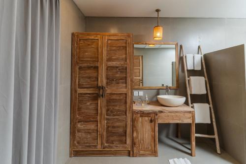 a bathroom with a wooden cabinet next to a sink at Vila Ombak in Gili Trawangan
