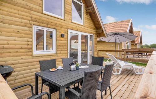 a wooden deck with a table and chairs and an umbrella at Awesome Home In Tranekær in Tranekær
