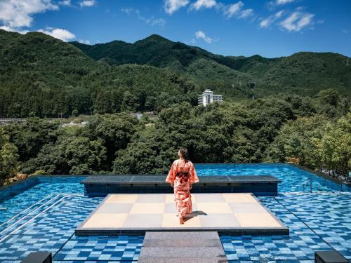 a woman standing on top of a pool with mountains in the background at Kinugawa Hotel Mikazuki in Nikko