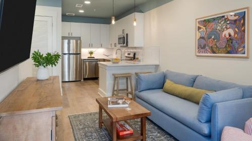 a living room with a blue couch and a kitchen at The Gilmore, an AvantStay Hotel in Nashville