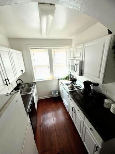 a kitchen with white cabinets and a wooden floor at (53.1S) Forest Park, The Zoo, and much more in Saint Louis