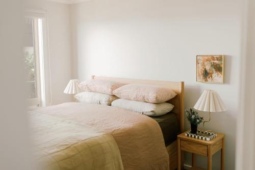 a bedroom with a bed with a stack of pillows at Phillip Island Shack in Smiths Beach