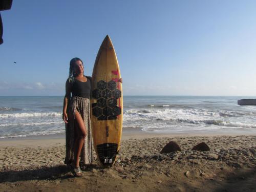 a woman standing next to a surfboard on the beach at Jumanji in Palomino
