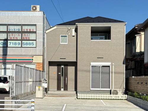 a brown house with a door on a street at The Maruko in Abiko