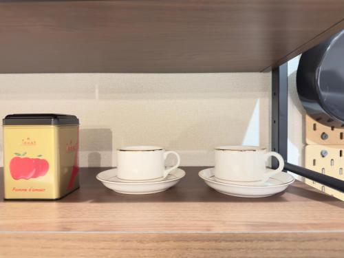 two coffee cups and a box on a shelf at The Maruko in Abiko