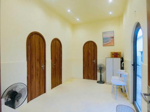 a room with wooden doors and a chair and a refrigerator at Le Cosmos Vĩnh Hy in Vĩnh Hy