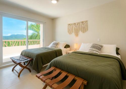 two beds in a room with a window at 2 Rec Vista a las Montañas I Amplia Terraza I Smart TV-Netflix I Wi-Fi I Recién Remodelado in Ixtapa