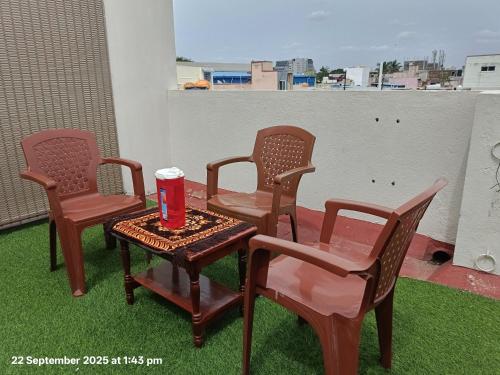 three chairs and a table with a cup on a balcony at Sundar Residency Near Annanagar Chennai in Chennai