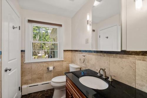 een badkamer met een wastafel en een toilet en een raam bij Spacious Home in Framingham MA in Framingham