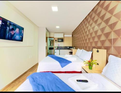 a hotel room with two beds and a flat screen tv at Studio A 350m PRAIA com Piscina 6 in Piçarras