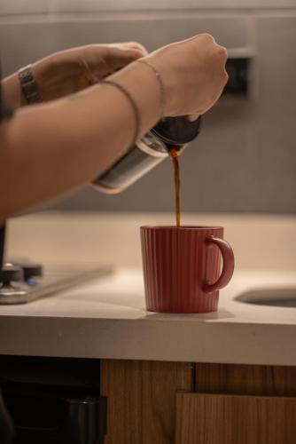 a person pouring coffee into a red cup on a counter at Autenthico Local Stay Hotel Envigado in Envigado
