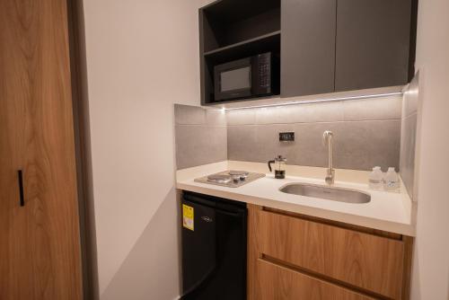a small kitchen with a sink and a microwave at Autenthico Local Stay Hotel Envigado in Envigado