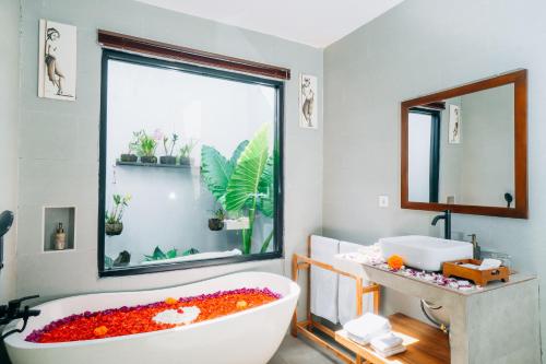 a bathroom with a tub filled with flowers and a window at Evandari villa in Ubud